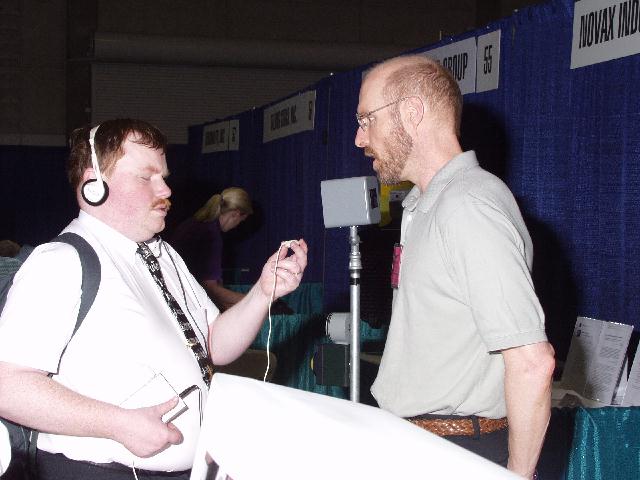Jonathan Mosen interviews an exhibitor at the Novax booth.