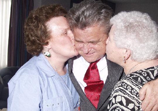 Janice Gable and Dot Taylor kiss Paul Edwards in thanks for their life
memberships.