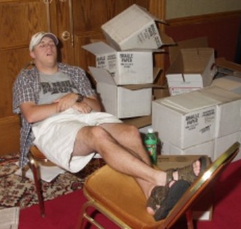 
Hard Day's Night: John Patterson dozes on two chairs after his
early morning delivery of The Lone Star Ledger.  On the floor
around him are boxes of braille paper, a local paper, and a half-
finished bottle of Mountain Dew.