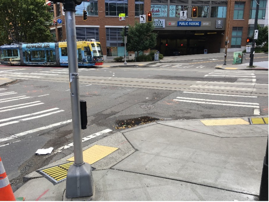 4-way intersection in Seattle showing raised bars installed on the two curb ramps at the two crossings from the closest corner