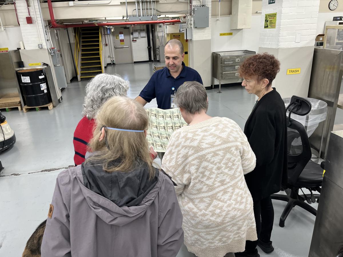 LEPE Supervisor John Bernhard shows a sheet of $20 notes to American Council of the Blind members during a visit to the DCF.